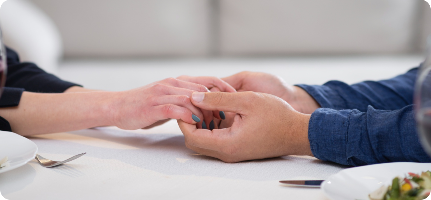 A couple seeking divorce counseling holding hands at a table.