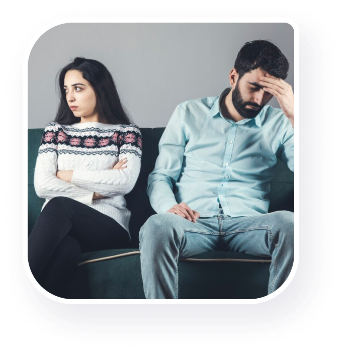A couple seeking therapy seated on a couch displaying distress.