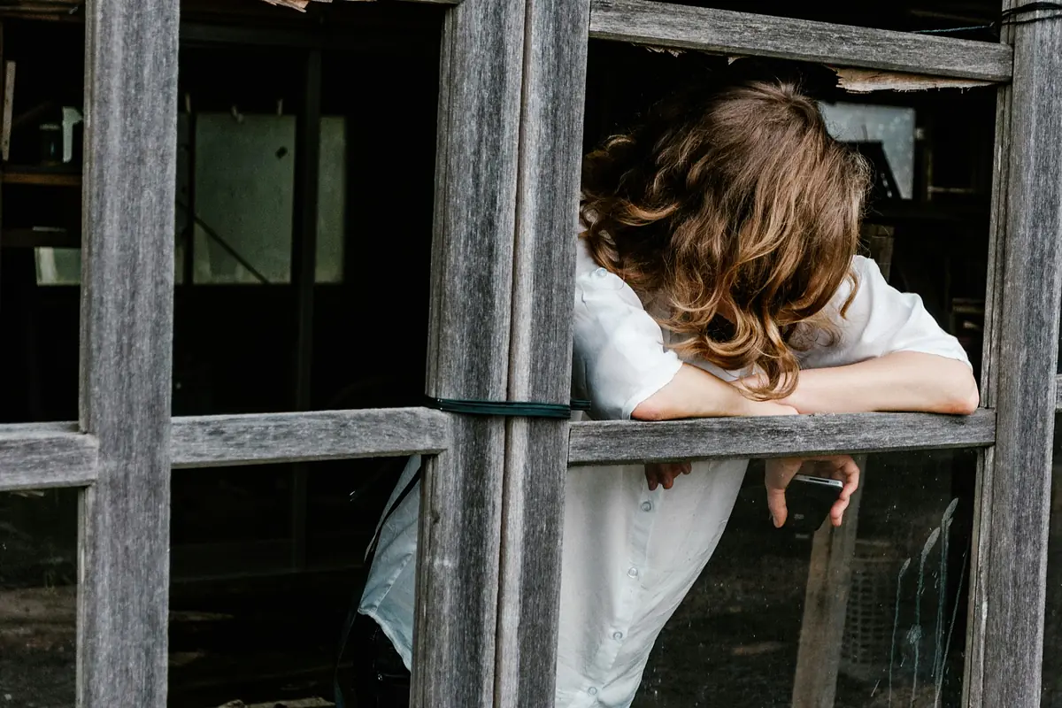 Woman leaning forward with her head resting on her folded arms