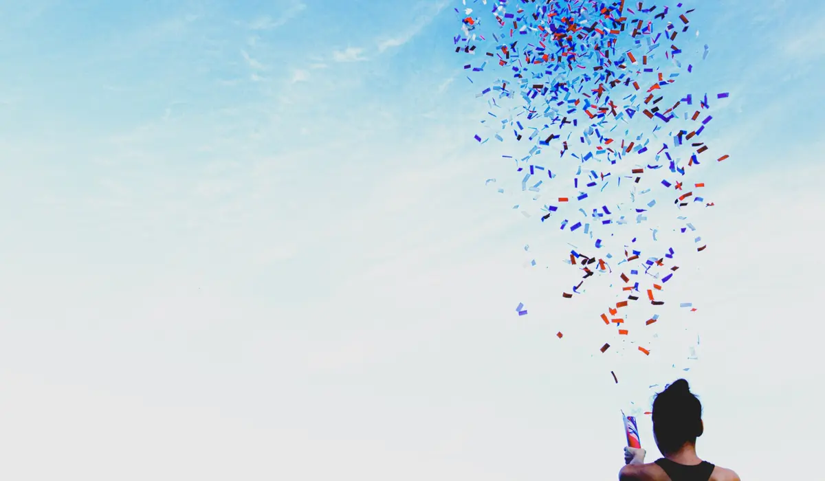 Person releasing colourful confetti into the sky